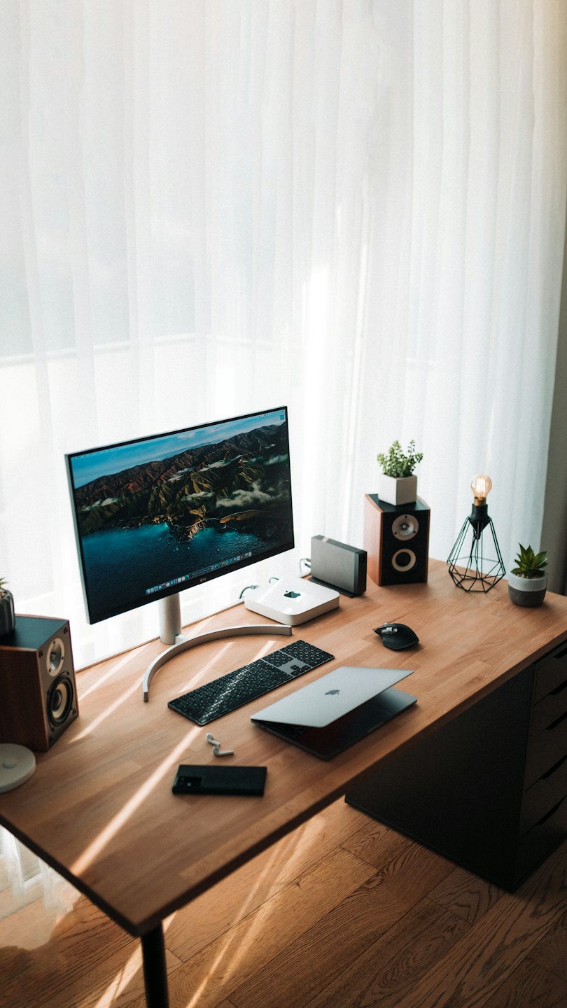 Ein moderner Schreibtisch mit Monitor, Laptop und Zubehör.